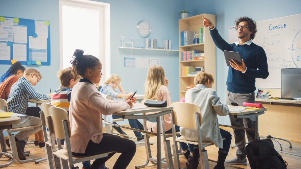 Enthusiastic Teacher Giving a Solar Energy Lesson in Elementary School to Class Full of of Diverse Children.